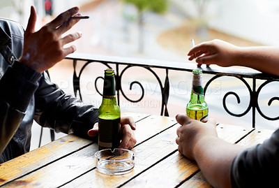 Buy stock photo A cropped image of two young men smoking with beers in front of them