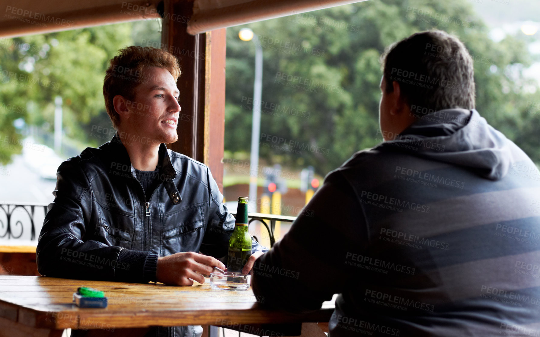 Buy stock photo Men, friends and drinking beer at a pub and restaurant with conversation and discussion. Alcohol, guys and young people together at diner with alcohol and drink with bottle and cigarette at table