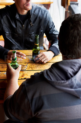 Buy stock photo Cropped image of two young men drinking beers at a restaurant