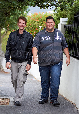 Buy stock photo A casually dressed young overweight man walking down the sidewalk with his buddy