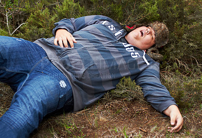 Buy stock photo An obese young man lying passed-out outside in the bushes
