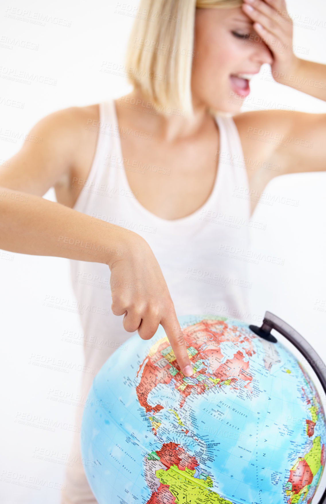 Buy stock photo A pretty young woman covering her eyes and pointing at her next destination on a globe