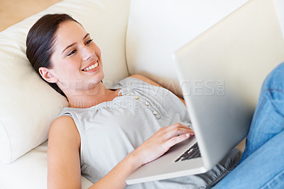 Buy stock photo Relax, happy woman and laptop on a sofa streaming, social media and reading in her home. Lying down, smile and female online in a living room with subscription, entertainment and internet search 