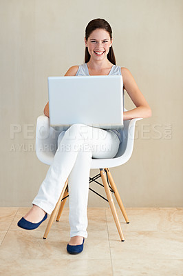 Buy stock photo A pretty young woman sitting in a chair and using her laptop