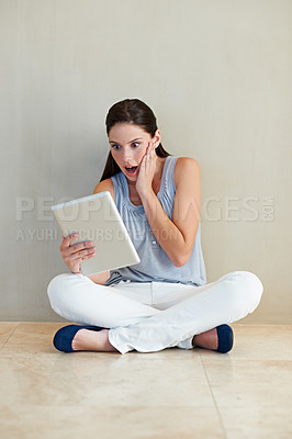 Buy stock photo Woman, tablet and surprised on social media, news or gossip sitting against a wall at home. Shocked female person, brunette or freelancer gasping on technology for notification, alert or information