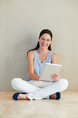 Buy stock photo A beautiful young woman using her tablet while sitting on the floor