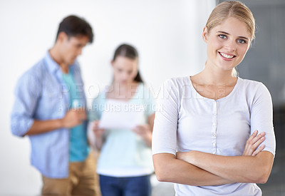 Buy stock photo A gorgeous young woman standing with arms folded with her colleagues in the background