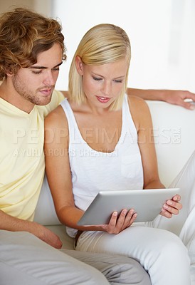 Buy stock photo Reading, tablet and young couple on sofa browsing on social media or internet at apartment. Relax, digital technology and happy man and woman from Australia scroll on website in living room at home.
