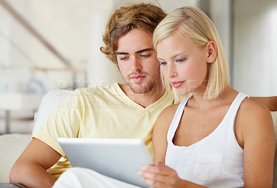 Buy stock photo Reading, tablet and young couple on sofa browsing on social media or internet at apartment. Relax, digital technology and man and woman from Australia scroll on website in living room at home.