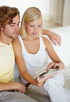 Buy stock photo Reading, tablet and young couple on sofa browse on social media or internet at apartment. Happy, digital technology and man and woman from Australia relax and scroll on website in living room at home