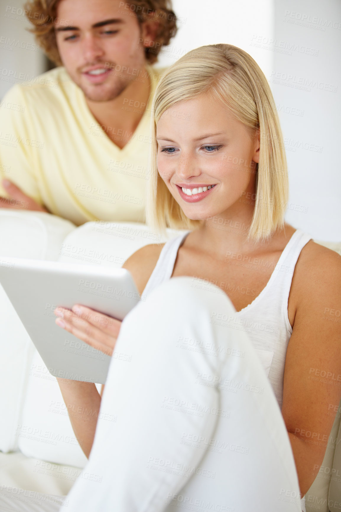 Buy stock photo A beautiful young woman using a tablet as her boyfriend watches from over her shoulder