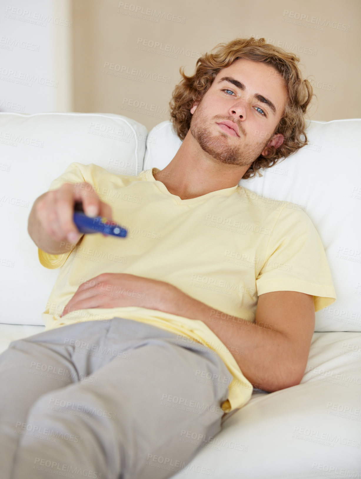 Buy stock photo A lazy young man flicking through TV channels