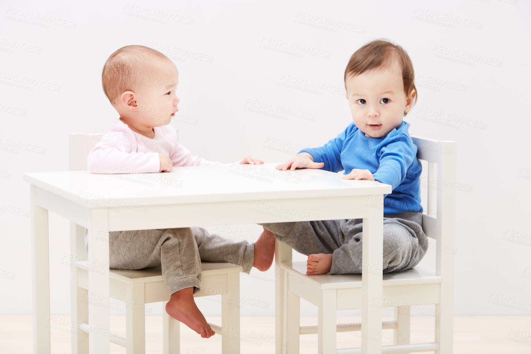 Buy stock photo Shot of two adorable little babies sitting together at a table