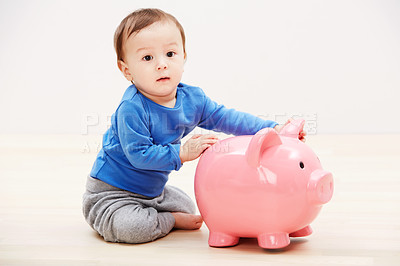 Buy stock photo Studio portrait of a baby boy playing with a  piggybank