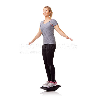 Buy stock photo A pretty young woman exercising on a balance board while isolated on a white background