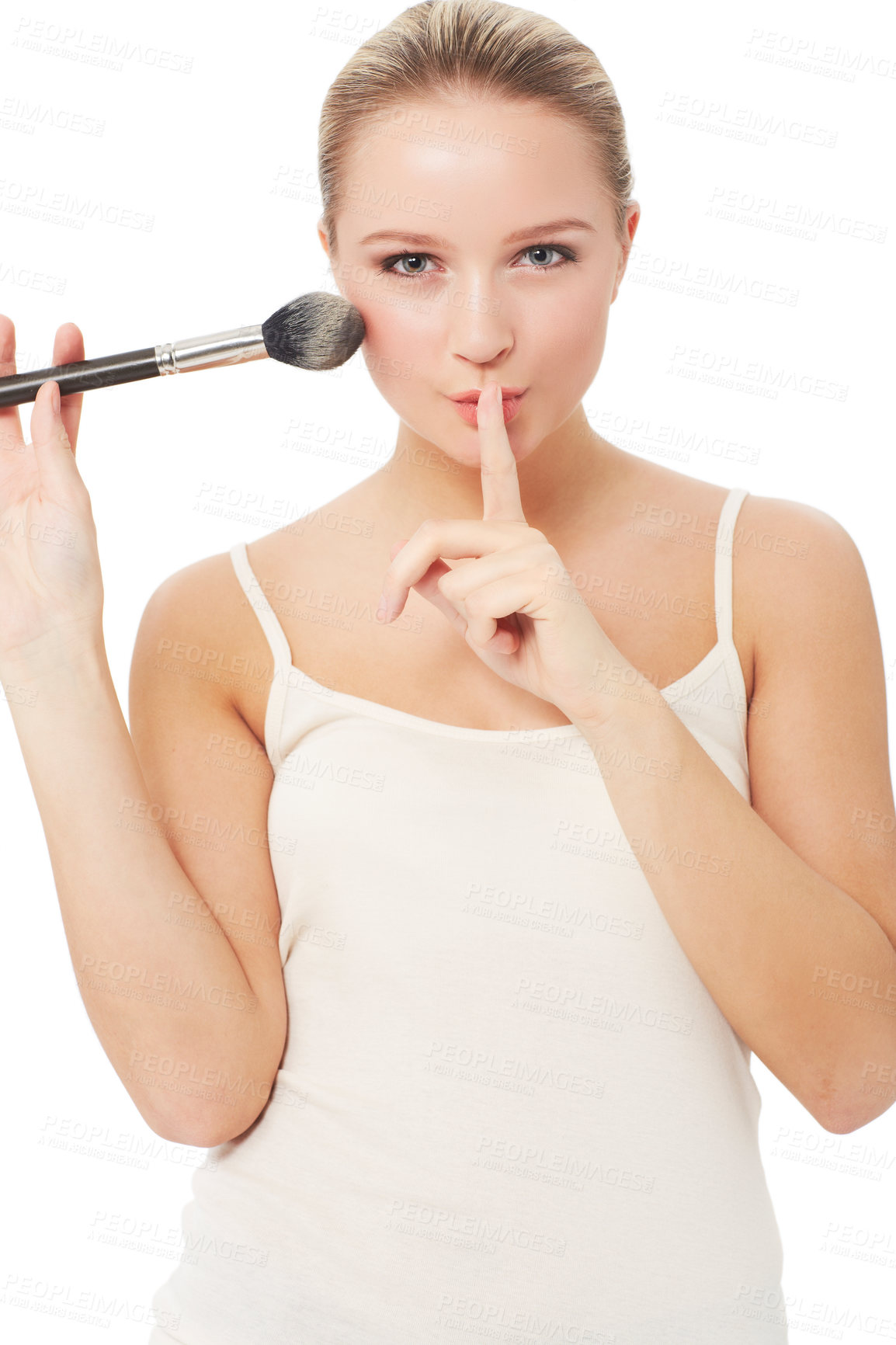 Buy stock photo A pretty woman putting a finger to her lips while applying blush to her face