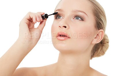Buy stock photo A gorgeous young woman applying mascara while isolated on white