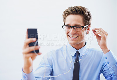 Buy stock photo A handsome young businessman choosing a song from his smartphone's playlist