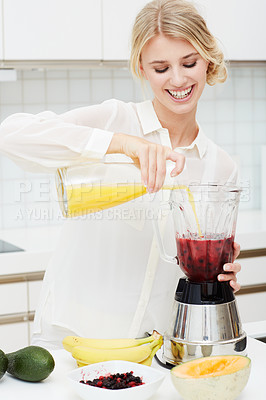Buy stock photo A beautiful young woman making a healthy shake with her blender