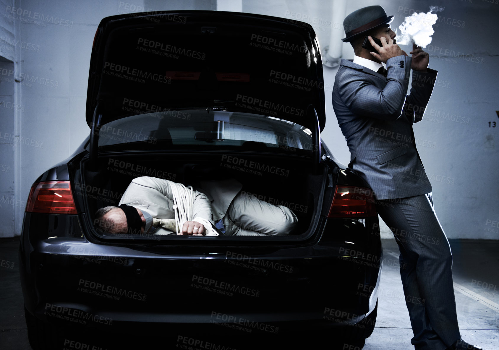 Buy stock photo Crime, car and man with hostage in trunk for negotiation, kidnapping ransom and phone call. Mafia, gangster criminal and businessman smoking in boot for abduction, danger and robbery in parking lot