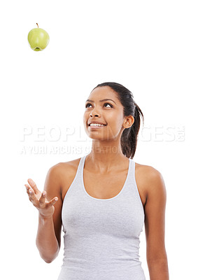 Buy stock photo A pretty young woman tossing an apple into the air while isolated on a white background