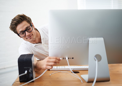 Buy stock photo A young man plugging  a cable into his computer