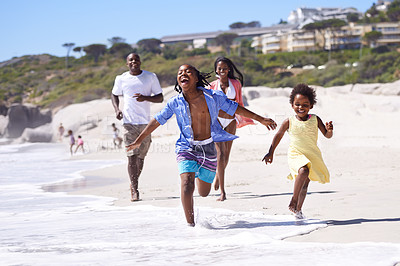 Buy stock photo A happy young african family running energetically along the beach