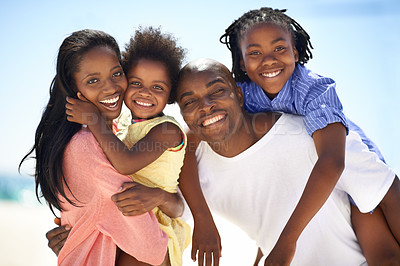 Buy stock photo Two parents giving their children a piggyback while on the beach