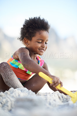 Buy stock photo An adorable young girl building a sand castle at the beach