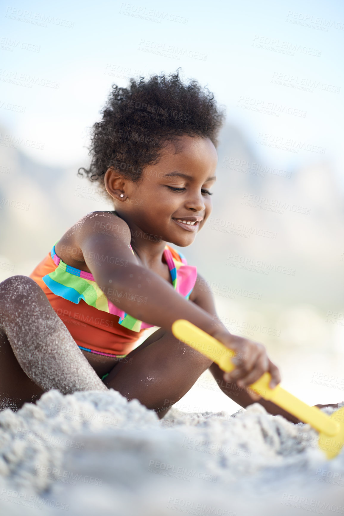 Buy stock photo An adorable young girl building a sand castle at the beach