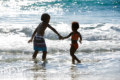 Buy stock photo Back, beach and kids holding hands in water at sea, love and together on summer holiday. African children, ocean and rear view of siblings, brother and sister on vacation, travel and family outdoor