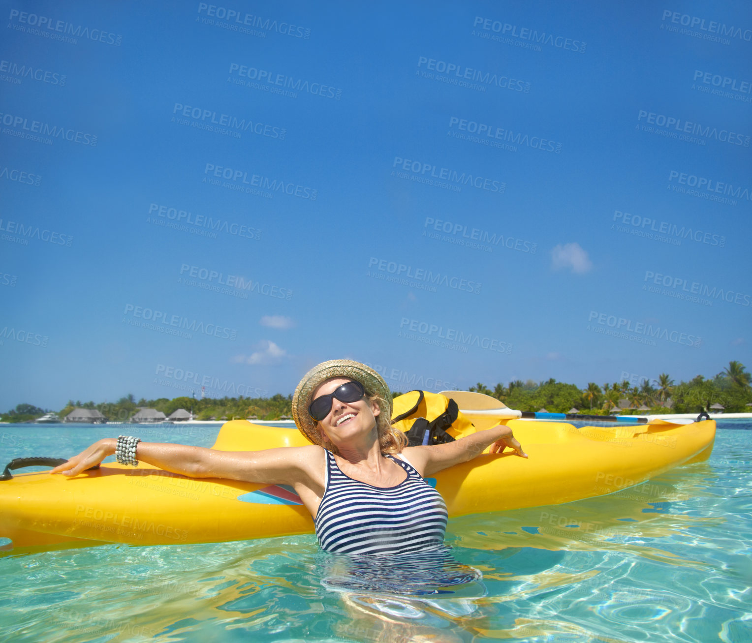 Buy stock photo A beautiful young woman relaxing in a tropical ocean with her boat