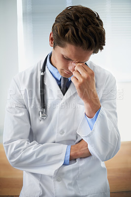 Buy stock photo Shot of an upset young doctor taking a moment to himself