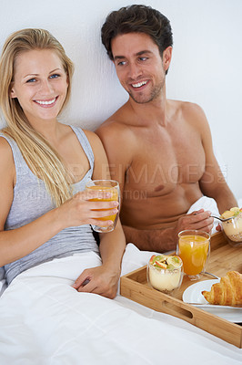 Buy stock photo Portrait of happy couple, morning and breakfast in bed to wake up with food or meal together to relax. Man, smile or woman in home eating healthy snack or drinking juice for diet for love in bedroom