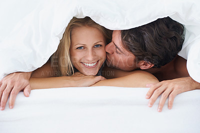 Buy stock photo Covers, portrait or happy couple kiss in bed on holiday vacation or romantic honeymoon in marriage. Morning, love or people with smile or joy in home, house or hotel together with duvet, bond or care