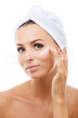 Buy stock photo Beautiful young woman applying beauty product on to her face while isolated against a white background