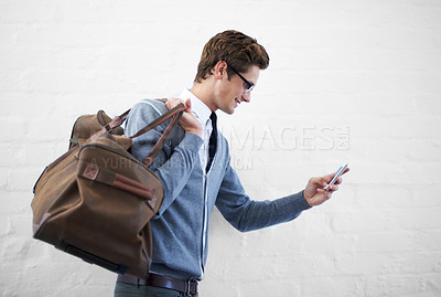 Buy stock photo Business man, bag and phone by wall background with click for booking app, schedule and happy on travel. Entrepreneur, employee and smartphone for smile, reading and scroll on web for flight schedule