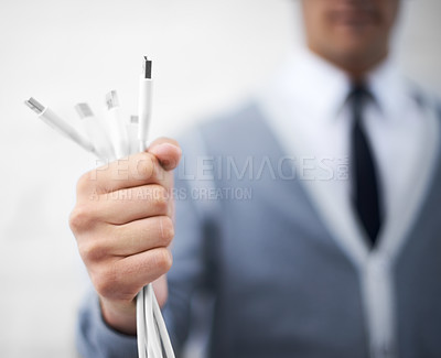 Buy stock photo A young nerdy guy holding usb cables toward the camera