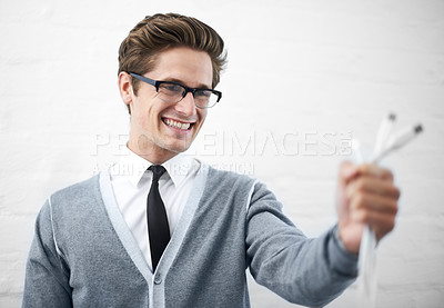 Buy stock photo A young nerdy guy holding usb cables toward the camera