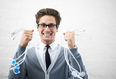 Buy stock photo A young nerdy guy holding up many cables while looking excited