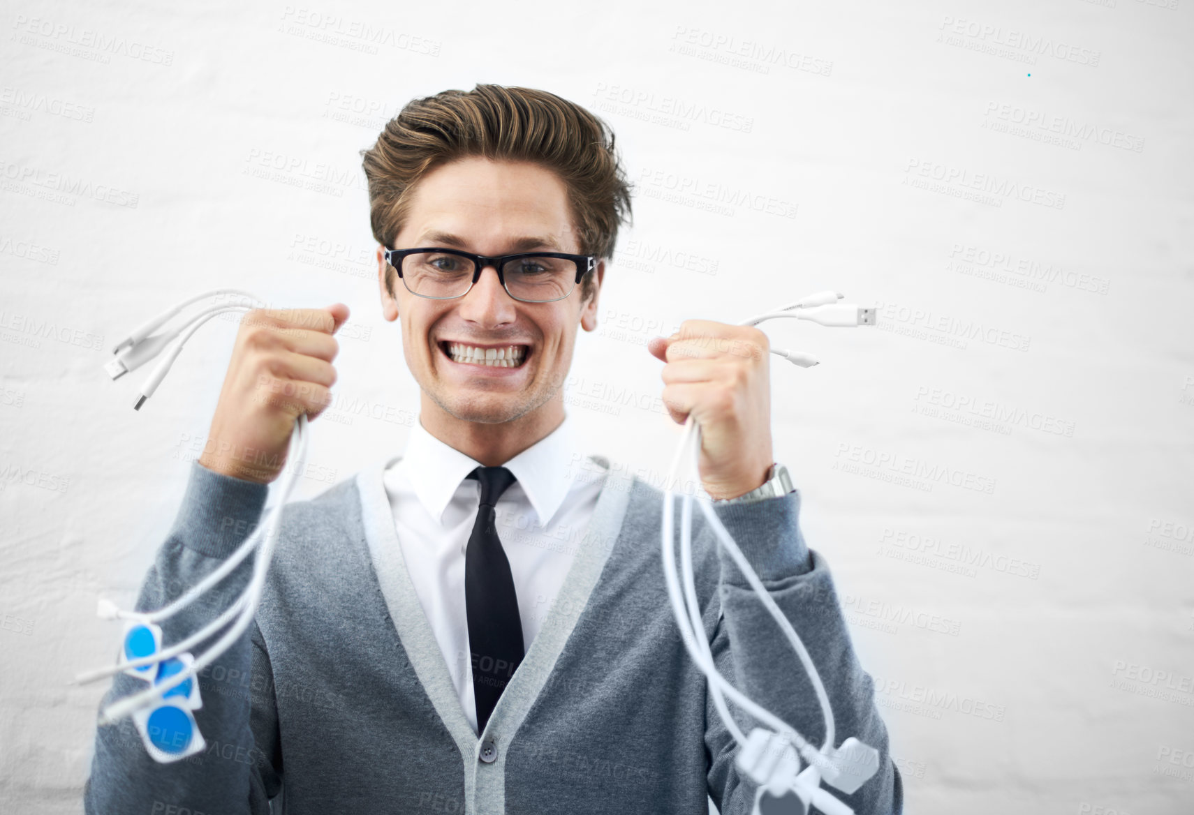 Buy stock photo A young nerdy guy holding up many cables while looking excited