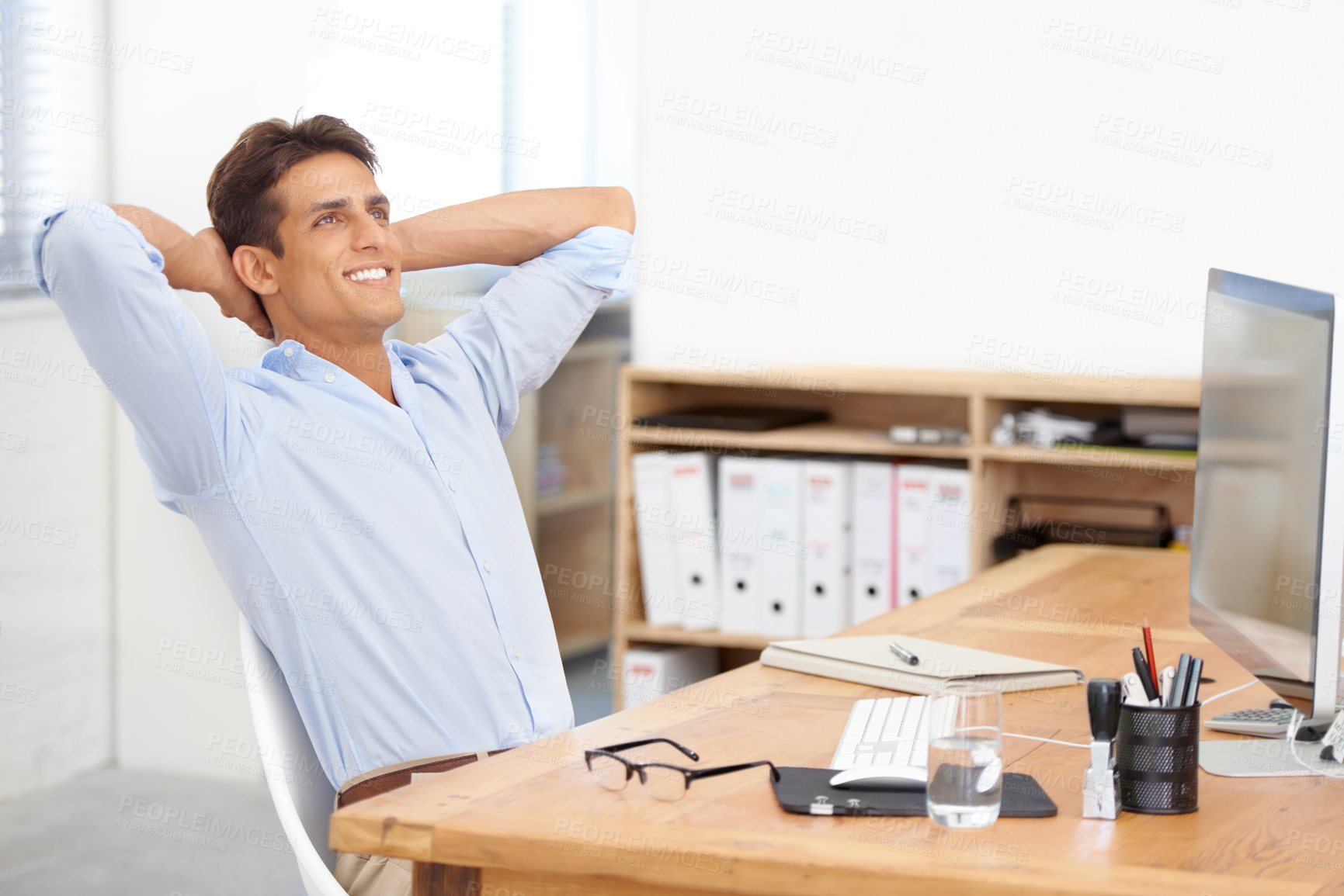 Buy stock photo Shot of a confident businessman sitting with his arms behind his head in his office