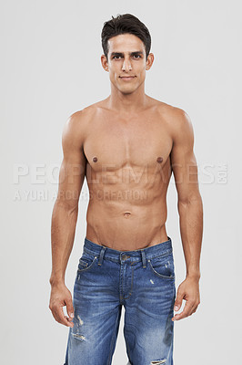 Buy stock photo Man, portrait and bodybuilder in studio for fashion, pride and confident in jeans for style. Male person, shirtless and fitness or muscle progress, face and body care or wellness by gray background