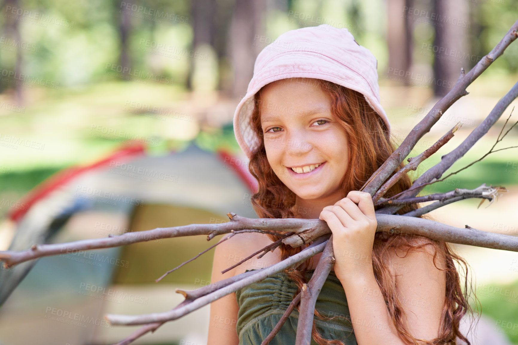 Buy stock photo Shot of a young girl holding twigs in front of her campsite