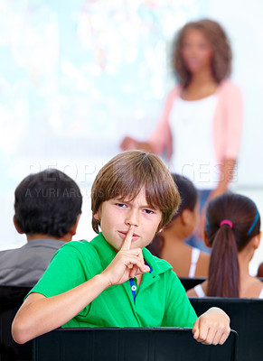 Buy stock photo Portrait, student or child in classroom with hush, gossip or fingers on lips for quiet learning. Sign, study or boy learner with whisper or shush gesture for rumor, loud noise or silence in school 