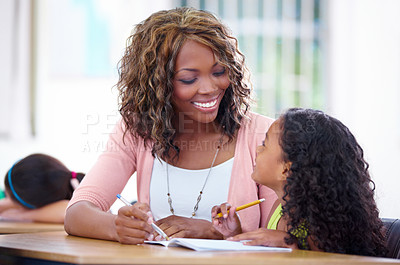 Buy stock photo A young teacher helping a pupil out with her schoolwork