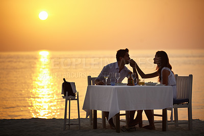 Buy stock photo Love, beach sunset and couple at table for romantic valentines day date at ocean in Bali in silhouette. Romance, food and wine on vacation for man kissing hand of woman during dinner in Indonesia.