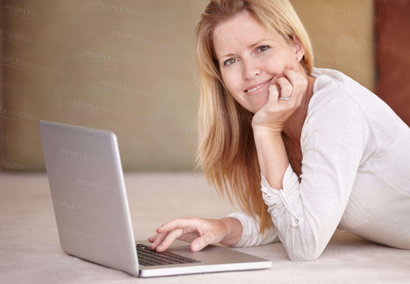 Buy stock photo A beautiful mature woman working on her laptop while lying on the floor