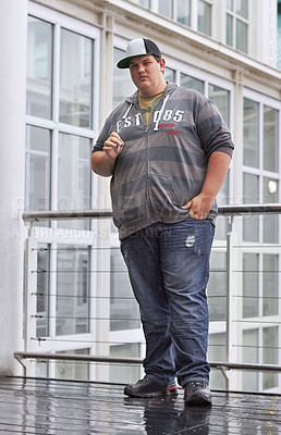 Buy stock photo Portrait of a young man standing outside for a quick smoke