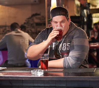 Buy stock photo Portrait of a young man drinking at the local bar